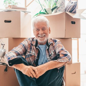 happy-senior-man-sitting-on-floor-relaxing-in-new-home-living-room-with-cardboard